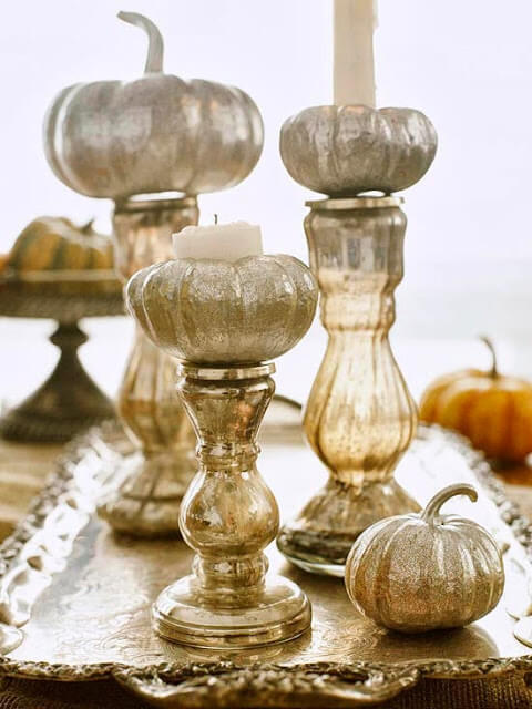 Elegant candle holders with spray-painted mini pumpkins on top.