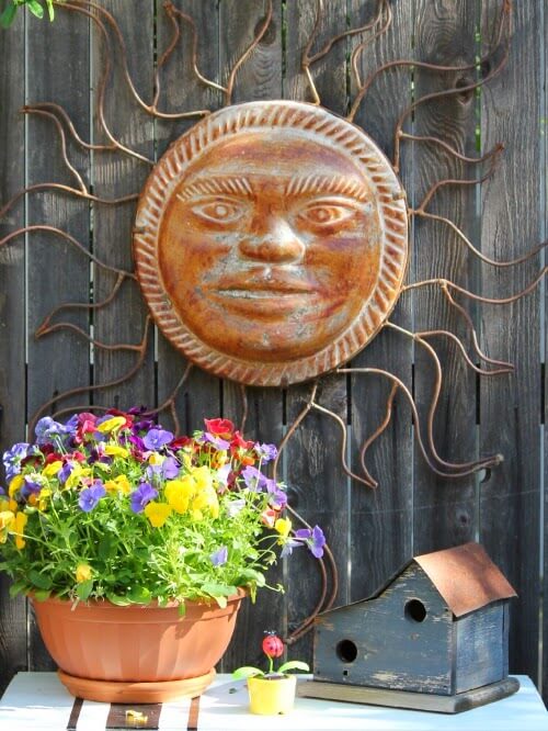 In creating an outdoor focal point, I used an old sewing machine table and put an old birdhouse on it along with a pot of pansies. My large sun is hung on the fence as the focal point.