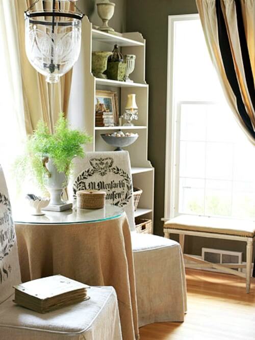 In Small Midwestern Home With European Style, the chairs were covered in a formal fashion and the open shelves display decor from all over the world.