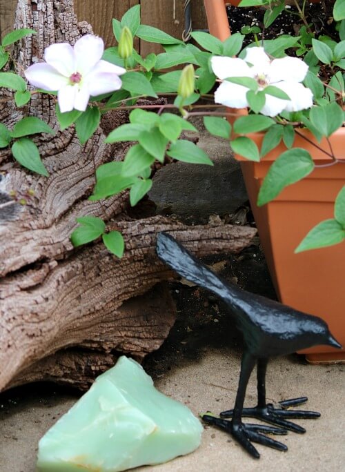 A steel blackbird next to a piece of driftwood