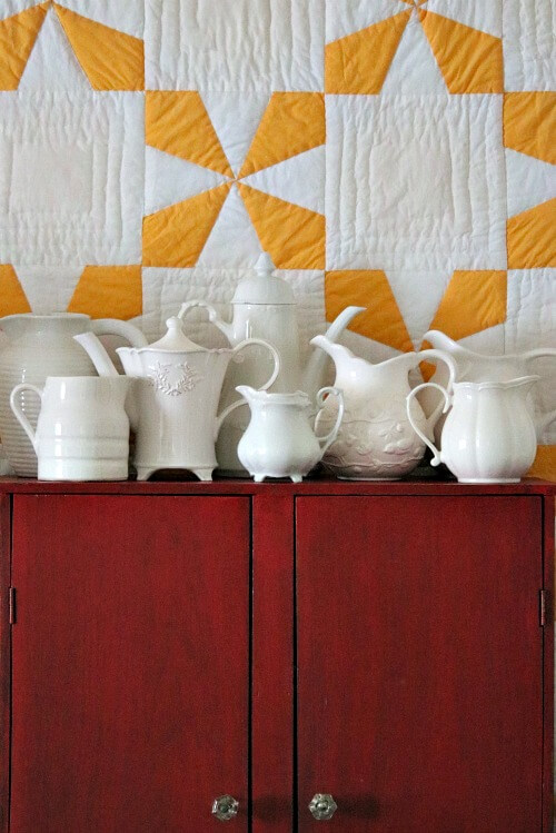 White pitcher collection on red cupboard
