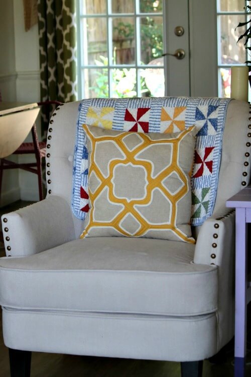 Change Up The Look Of Furniture Without Spending Money by layering a throw pillow over a small quilt.