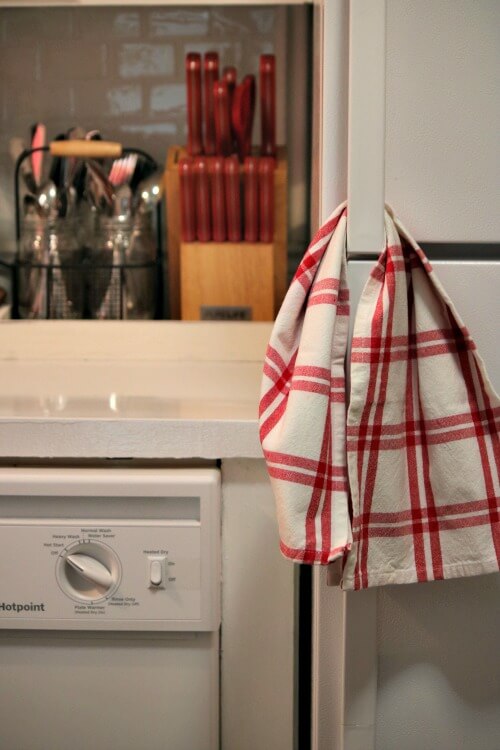 A red and white dish towel hanging through the fridge door handle