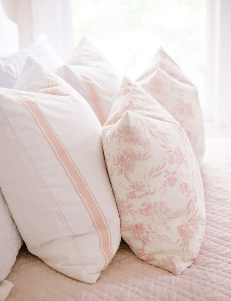 pink and white pillows on a bed