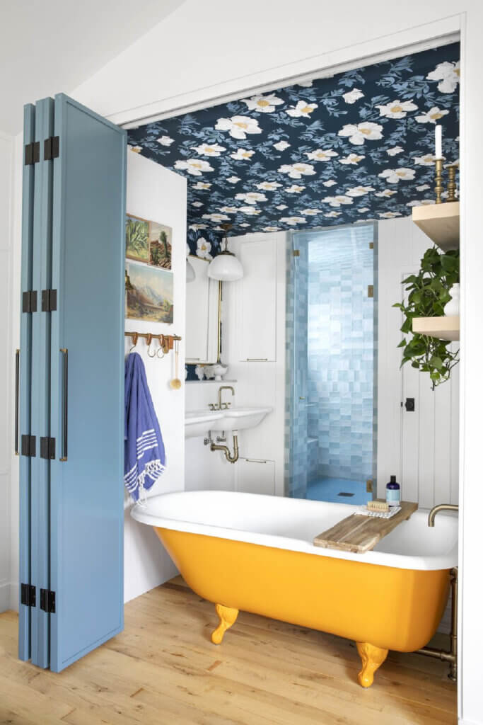 The bathroom has blue bi-fold doors that enclose a gold and white claw foot tub in this dreamy 1950s Southern California Cottage