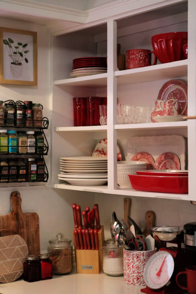 A view of my new red ceramic bakeware on the lower shelf of my open kitchen cabinets.