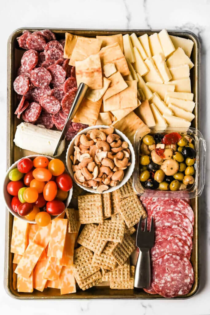 A budget charcuterie board with cheese, crackers, nuts, meats and olives