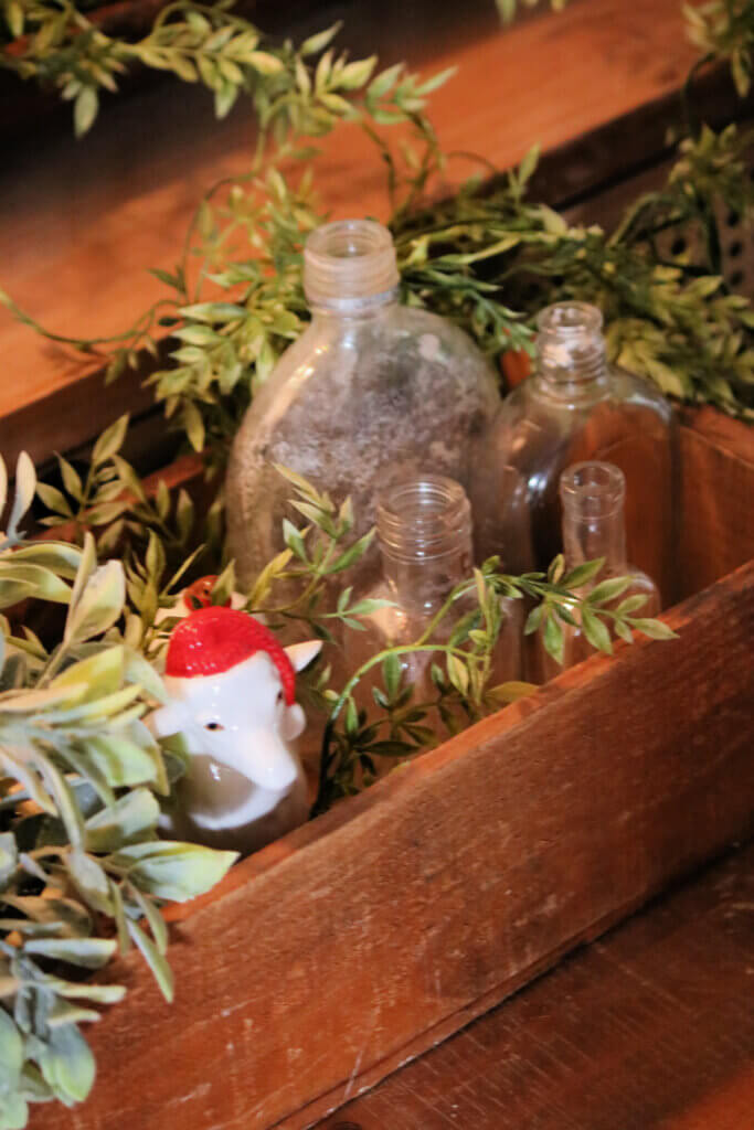 In a Christmas vignette 2021 I have a vintage box with vintage bottles and a lamb with a red Santa cap on