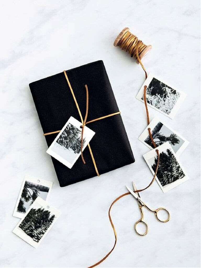 In 8 Unique Christmas Gift Wrapping Ideas, this classic idea is to use dark paper and Poloroid snapshots