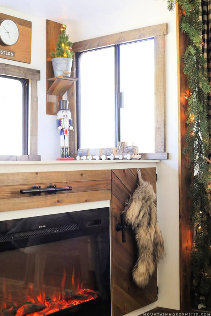 In decorating your RV for Christmas, this is the fireplace all lit up and surrounded by greenery in Mountain Modern Life.