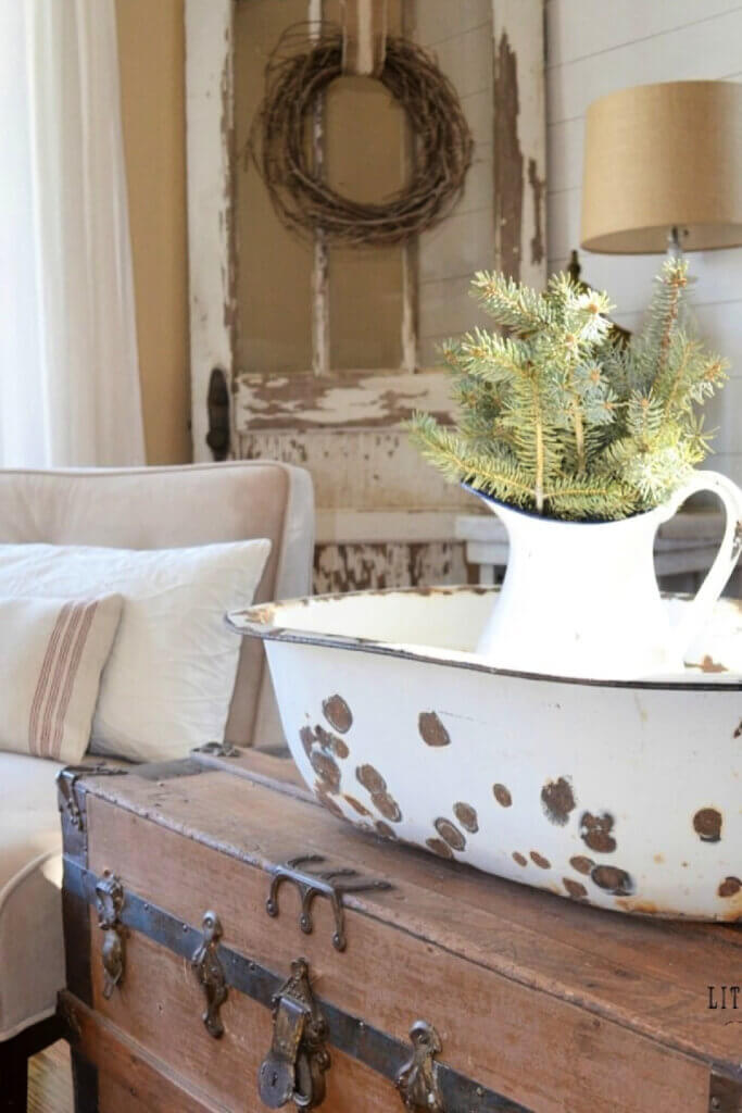 In Easing Into Winter Decorating, this old trunk holds a weathered tub and a white pitcher of greenery