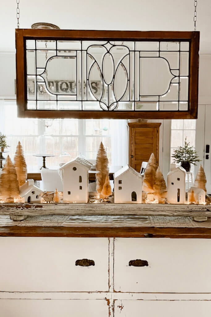 These two bloggers created a village on the surface of a piece of furniture. There they displayed white ceramic houses and brass bottle brush trees