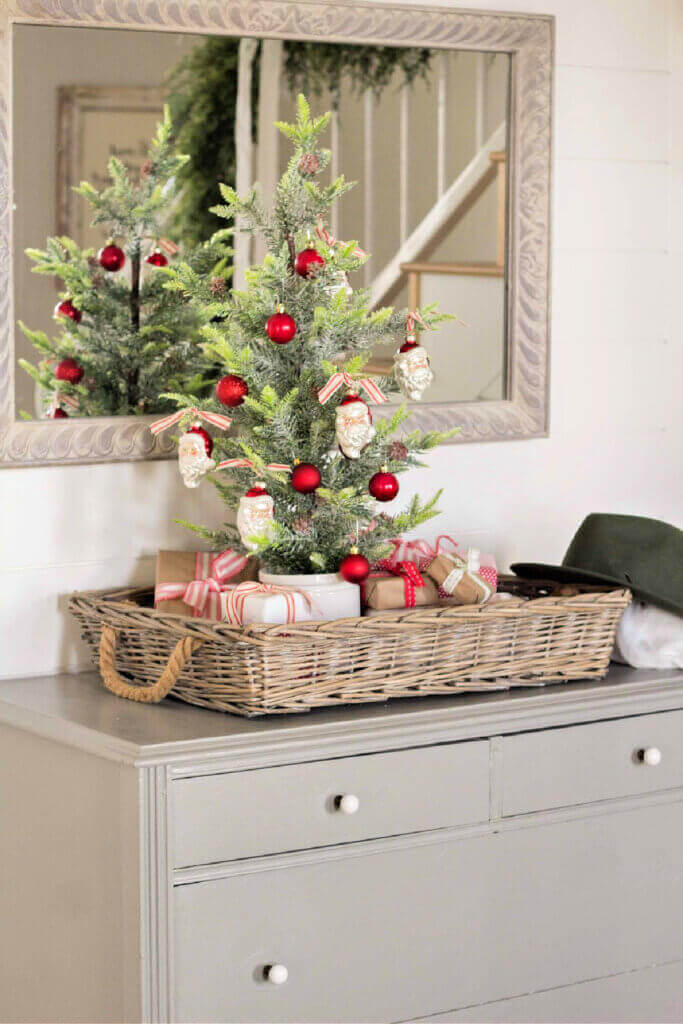 In Tabletop Christmas Decor Ideas, this blogger fashioned a cute little Christmas tree in a rectangular wicker basket in front of a wall mirror.