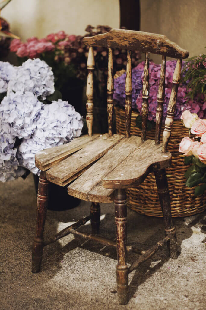 An old weathered chair surrounded by baskets of hydrangeas