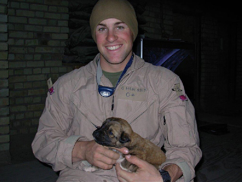 Clay Hunt, in military clothing, holding a puppy.