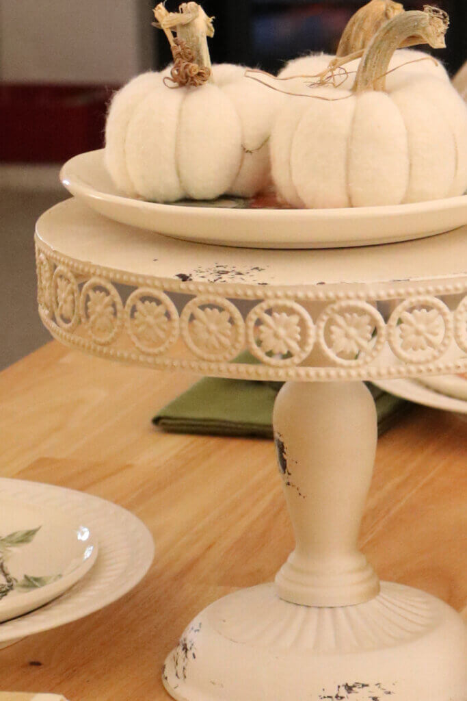 In a cozy autumn dining room, I used a tiered tray for the centerpiece with three soft neutral pumpkins.