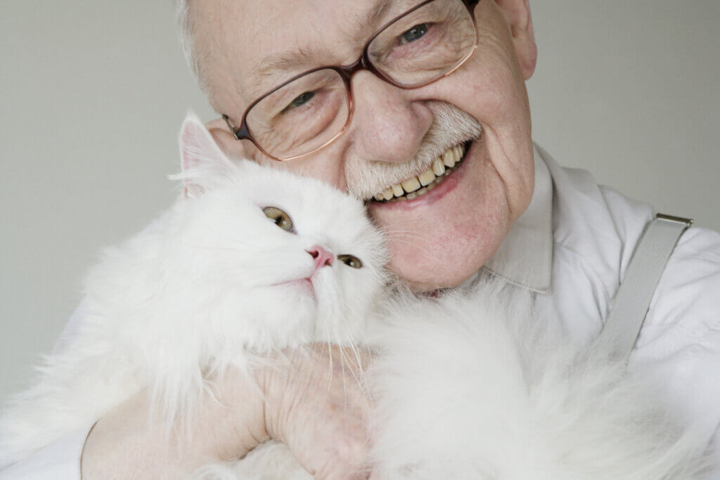 An elderly man with his beloved white cat.