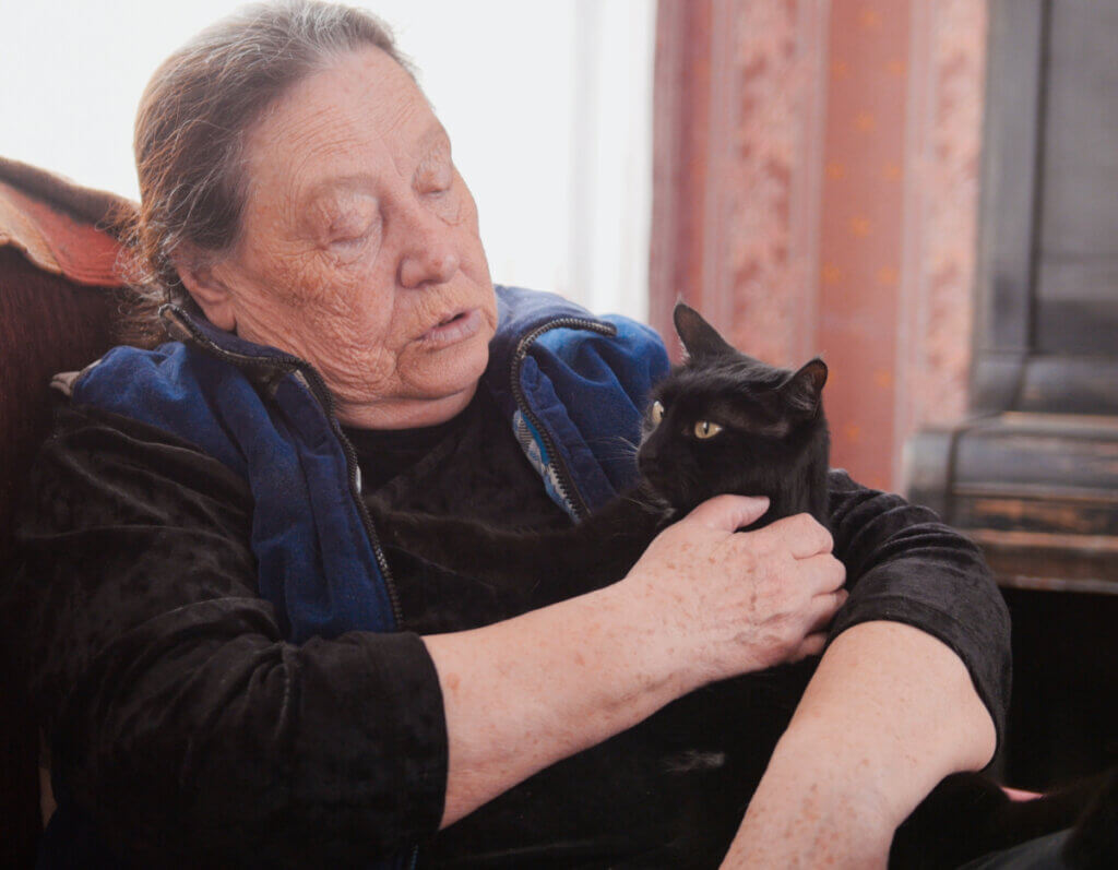A senior woman holding her black cat