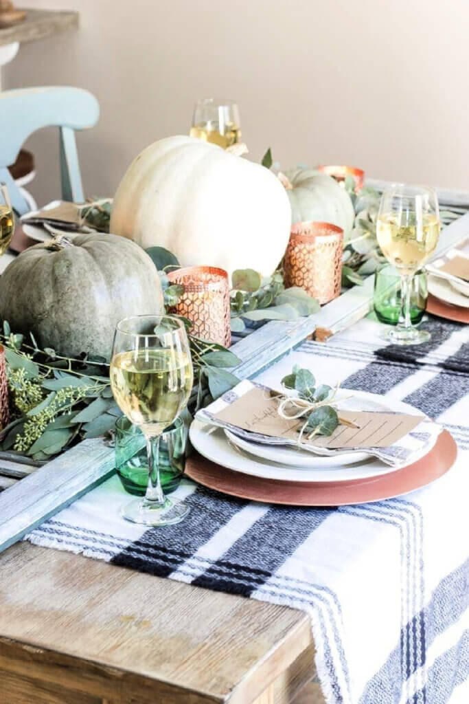 A casual table setting with a weathered shutter for the centerpiece, with pumpkins and candles on top.