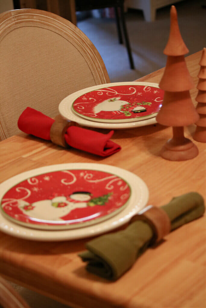 A holiday tablescape with a trio of wood Christmas trees for a centerpiece.