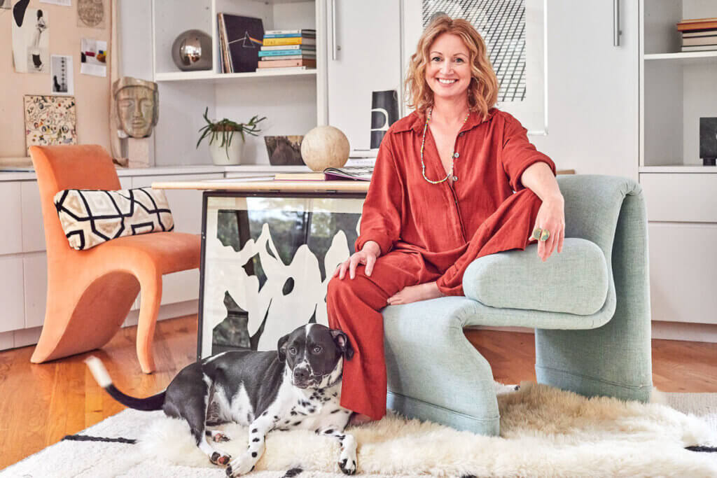 In A Collector's Colorful New York Home, Corrin Arasa sits in her home with her dog.