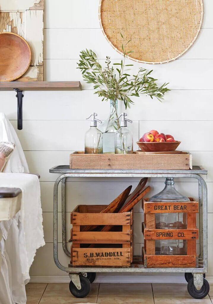 In A Flea Market Filled Family Home, there is a vintage rolling cart with old wood crates underneath