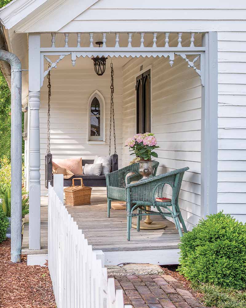 In A Charming Cottage In Tennessee, the porch has a swing and two faded turquoise wicker chairs.