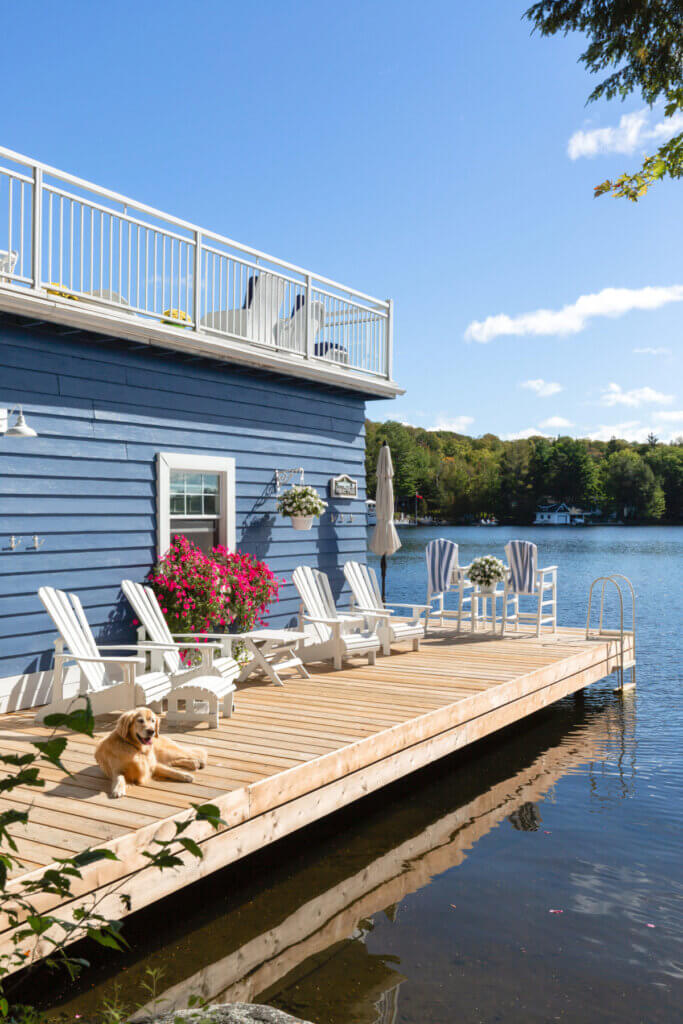 In A Lakeside Property Named Jubilee, you see cool blue water surrounding their blue and white cottage.