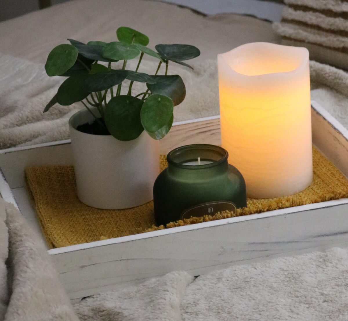 A wood tray with candles and a plant