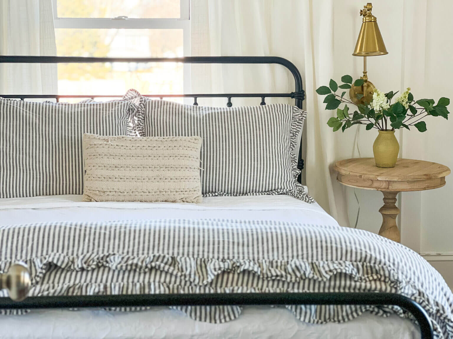 Blue and white striped bedding and black iron headboard.