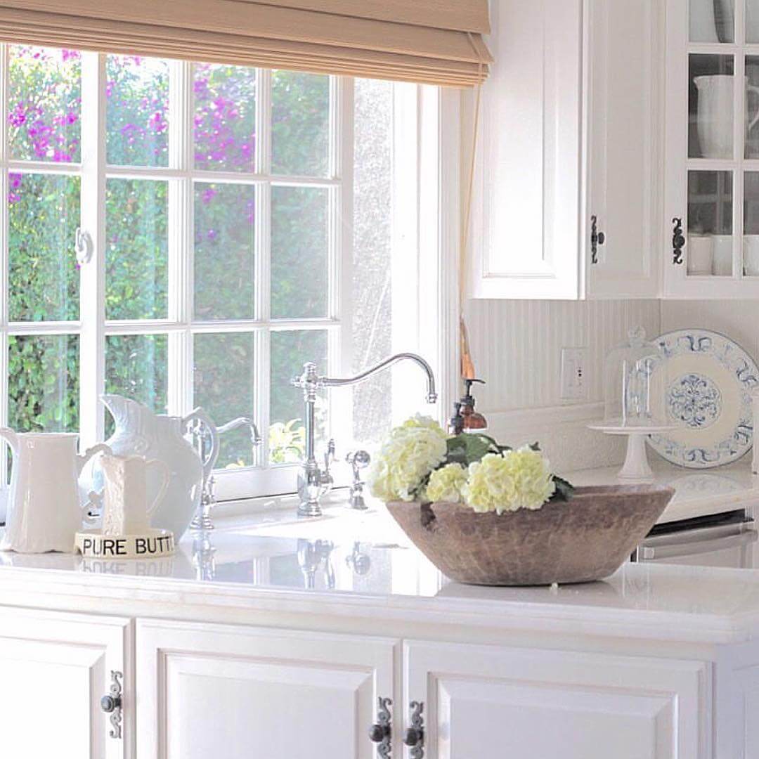 In Cozy Cottage Minimalist Rooms & Decor, this is a White kitchen with a bowl of white hydrangeas
