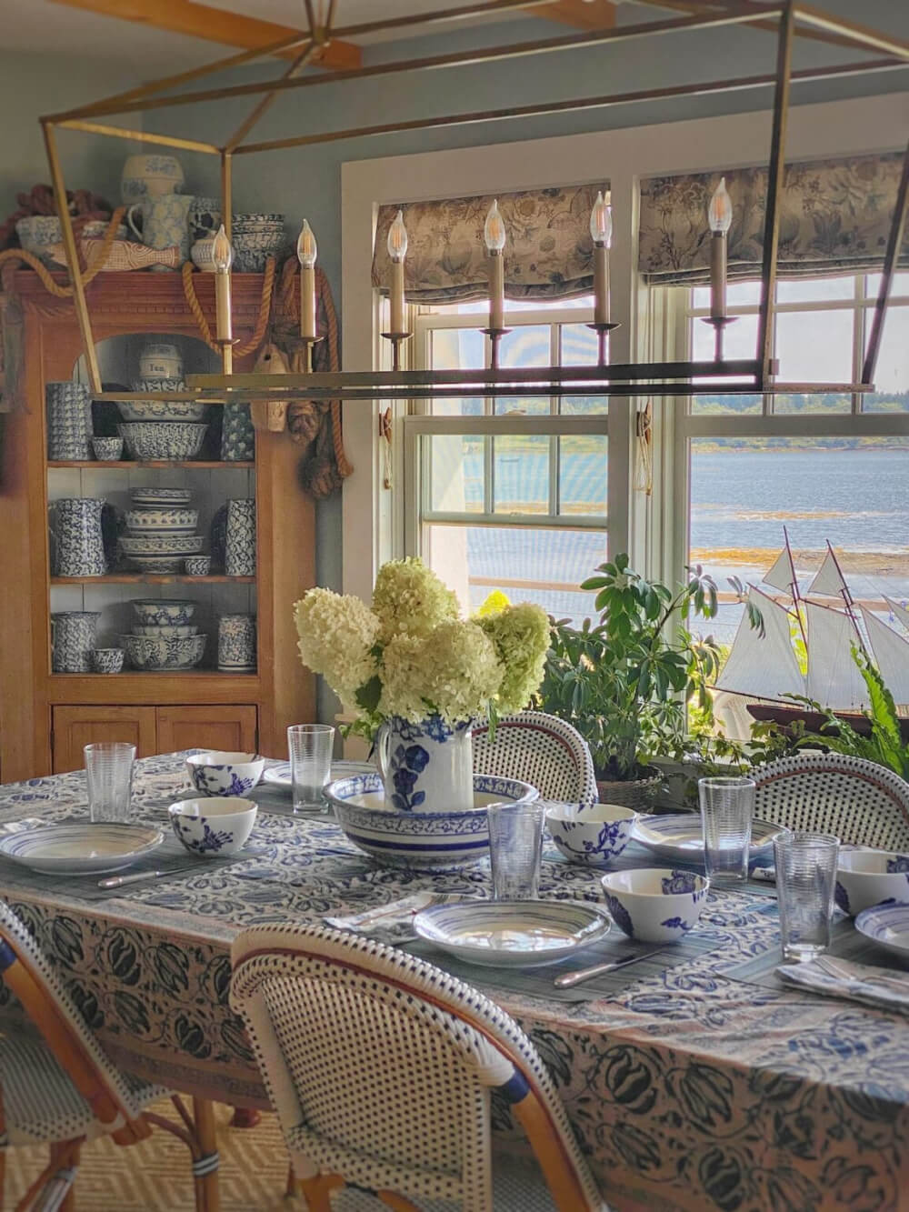 In The Love Of Home Files #4, a blue and white themed dining room with a corner hutch looking out over water