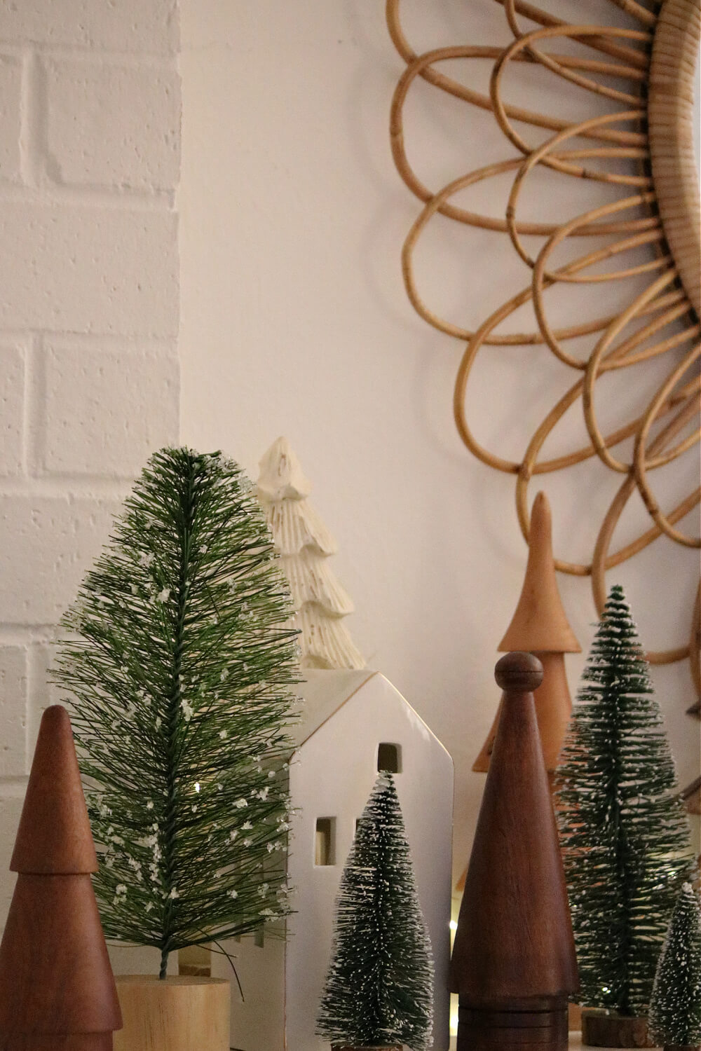 Wood trees and bottle brush trees layered on my mantel with white ceramic houses.