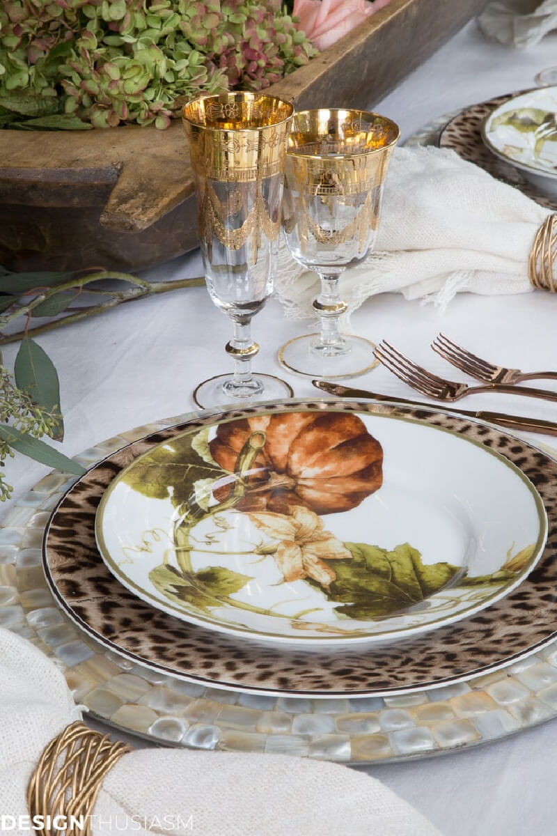 Gold and glass wine glasses on the table with a leopard charger and pumpkin plates