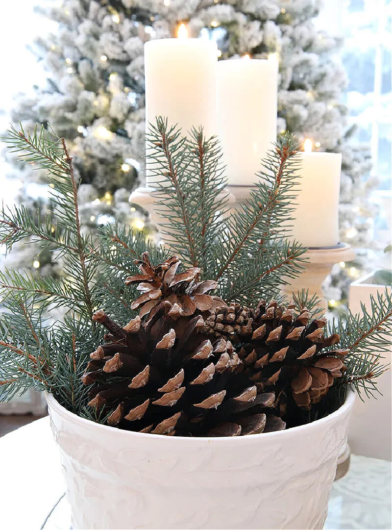 An arrangement of candles, greenery and pine cones