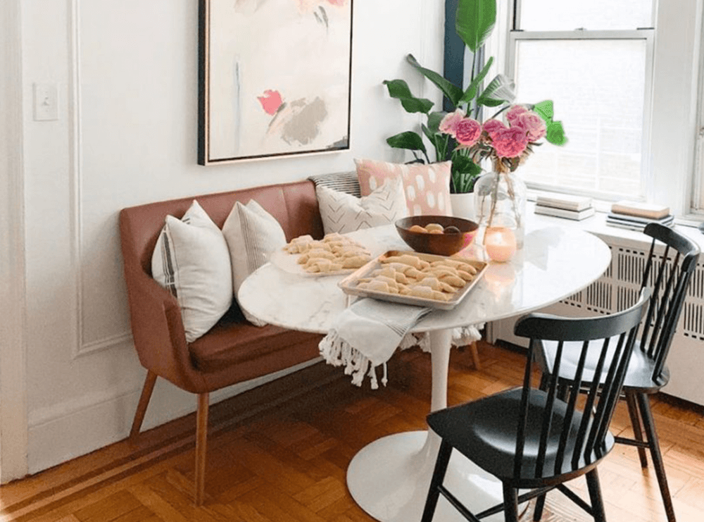 A loveseat serves as a banquette against the wall with a tulip table and two black chairs.