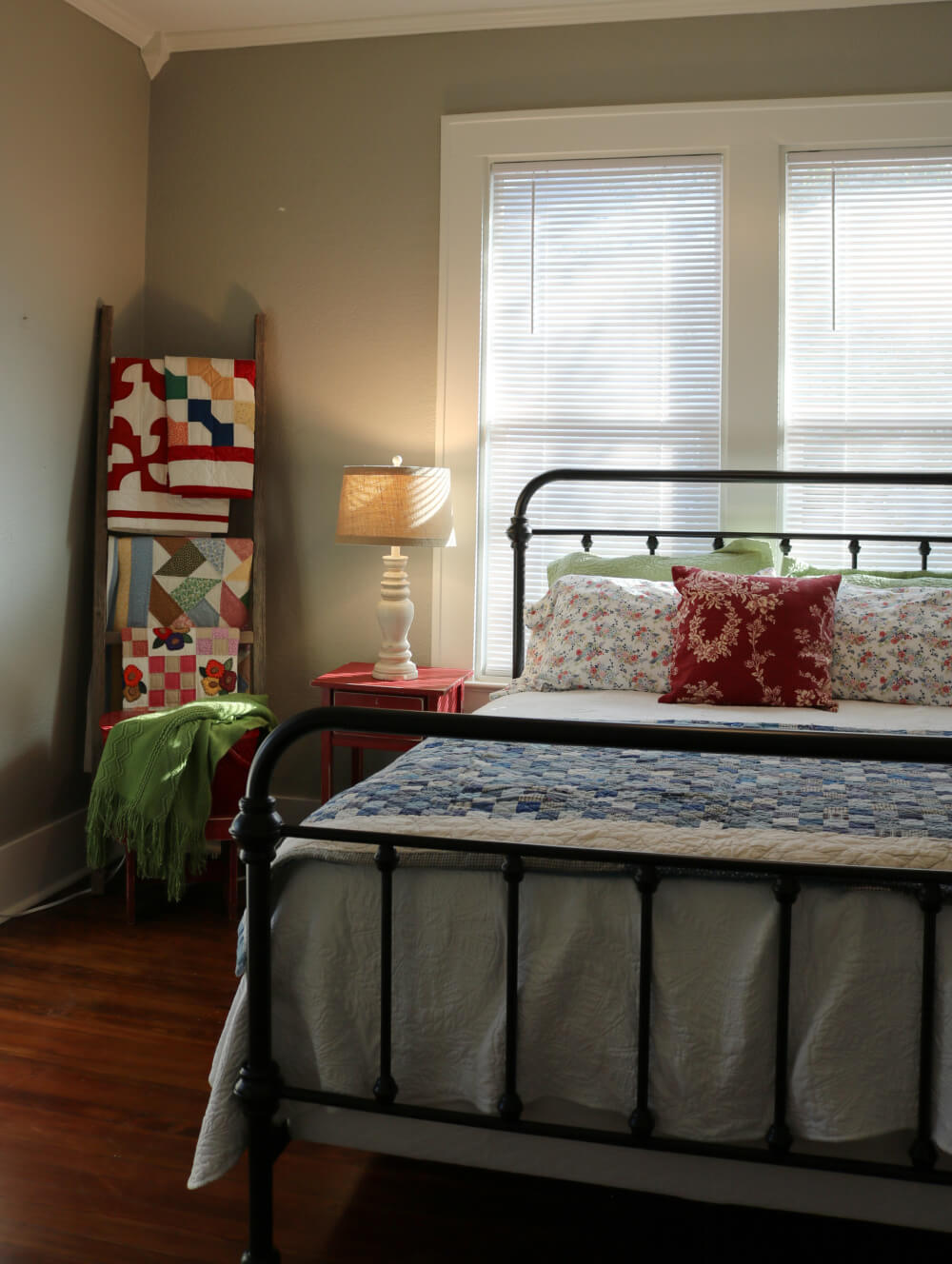 Lighting creates a cozy ambiance in my guest room with a neutral lamp and shade on a red side table.