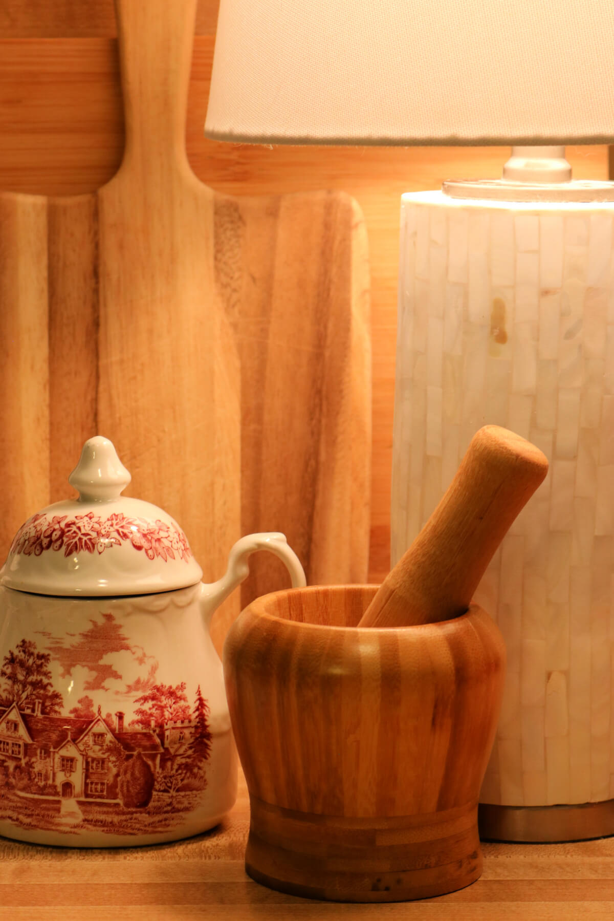 A small lamp on a kitchen counter with cutting boards behind it.