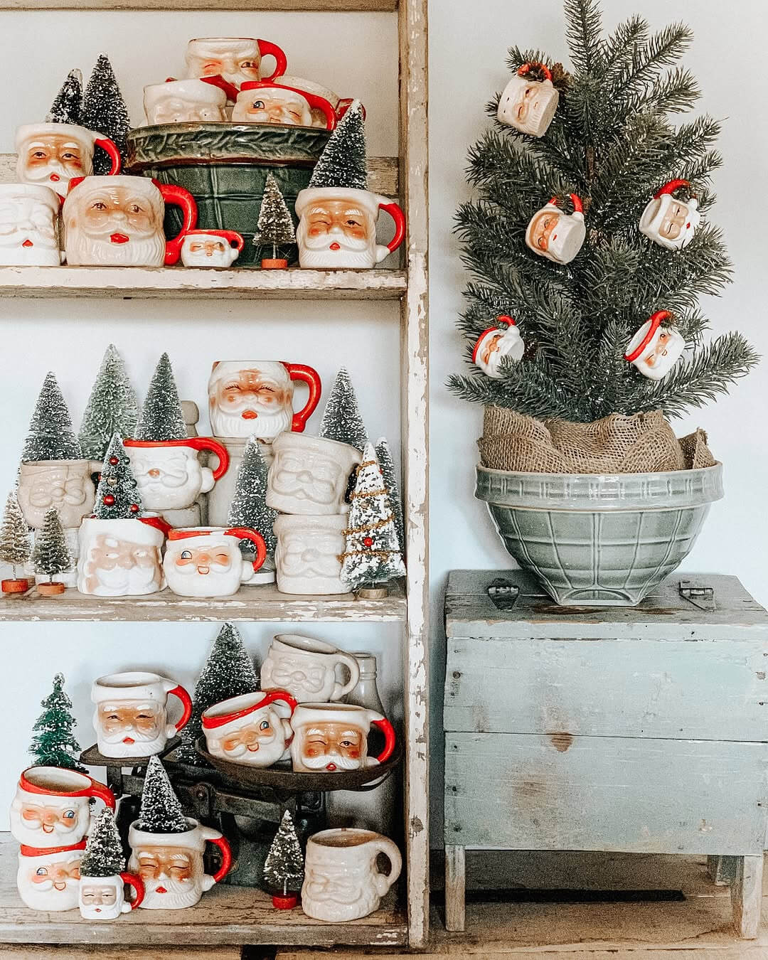 Deck the Halls with Santa Mugs on a chippy white shelf next to a tabletop tree with mug ornaments in a large bowl.
