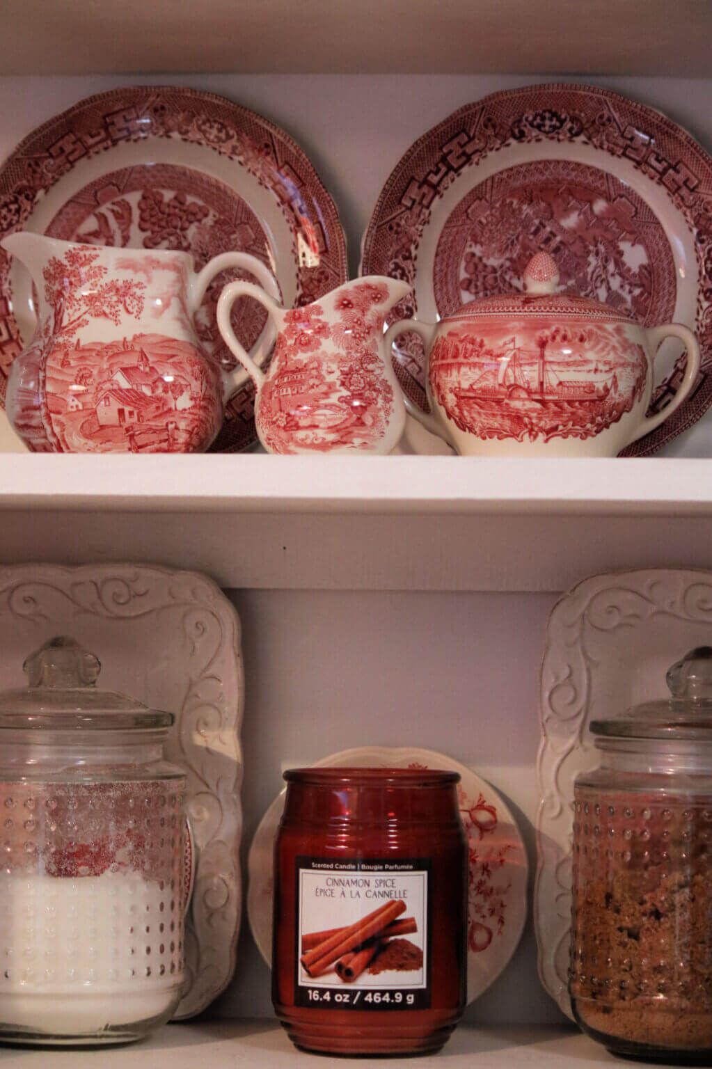 Red and white transferware in open cabinets at an old apartment.