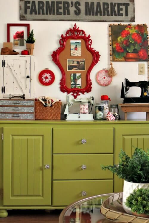 A mini office space in a small apartment I lived in. A green cupboard, with vertical storage and a red bulletin board. Two Singer featherweight sewing machines.