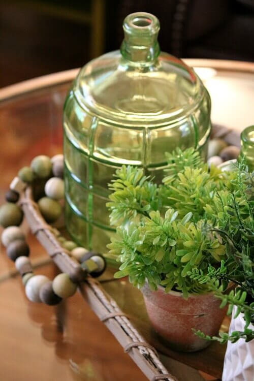 Admiring Decor Without Wanting to Redecorate with this tobacco basket and green bottle and faux greenery and bead garland.