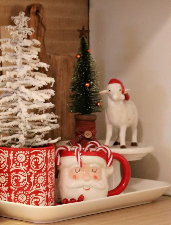 A corner vignette has several little trees and a white lamb with a Santa hat looks outward.