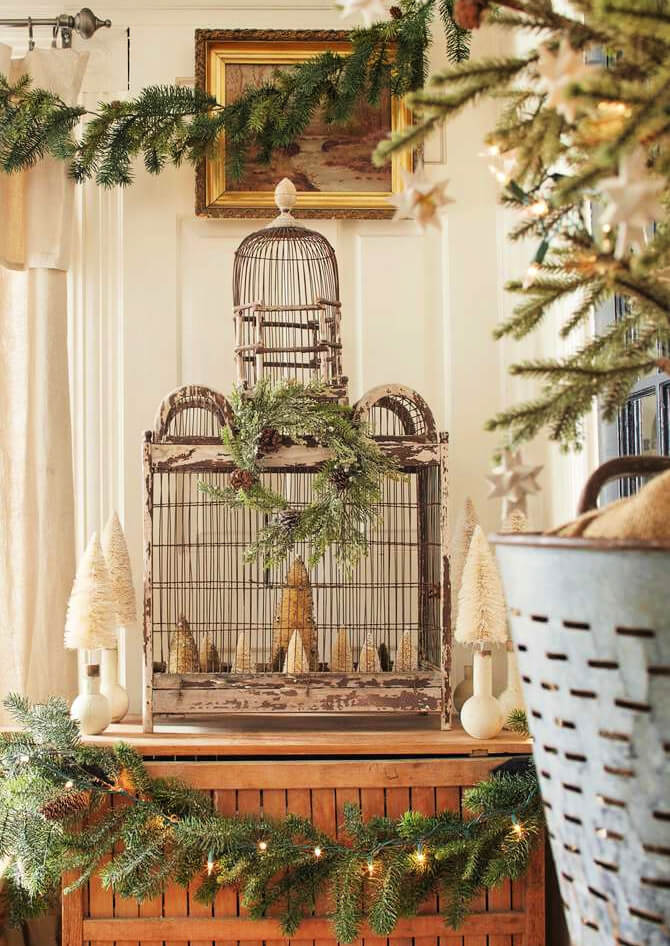 Budget-Friendly DIY holiday decorations is this chippy birdcage with bottle brush trees inside.