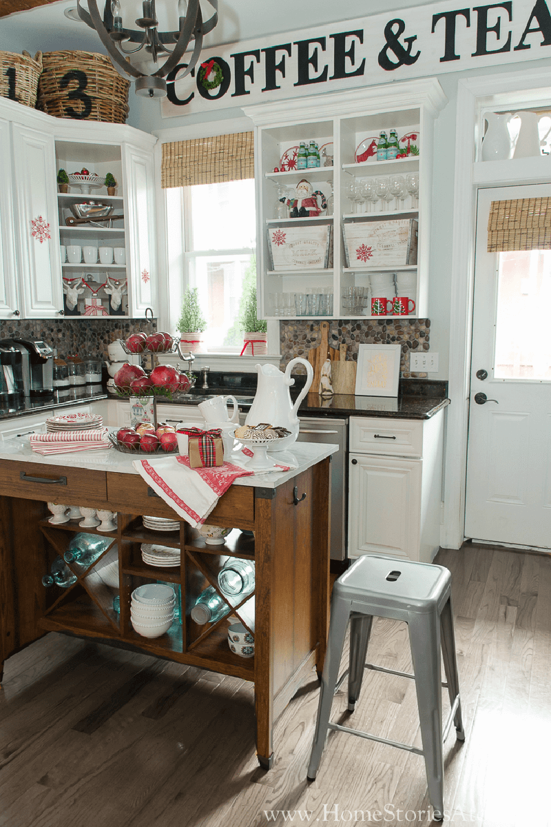 A Christmas kitchen with open cabinets and holiday decor on the island.