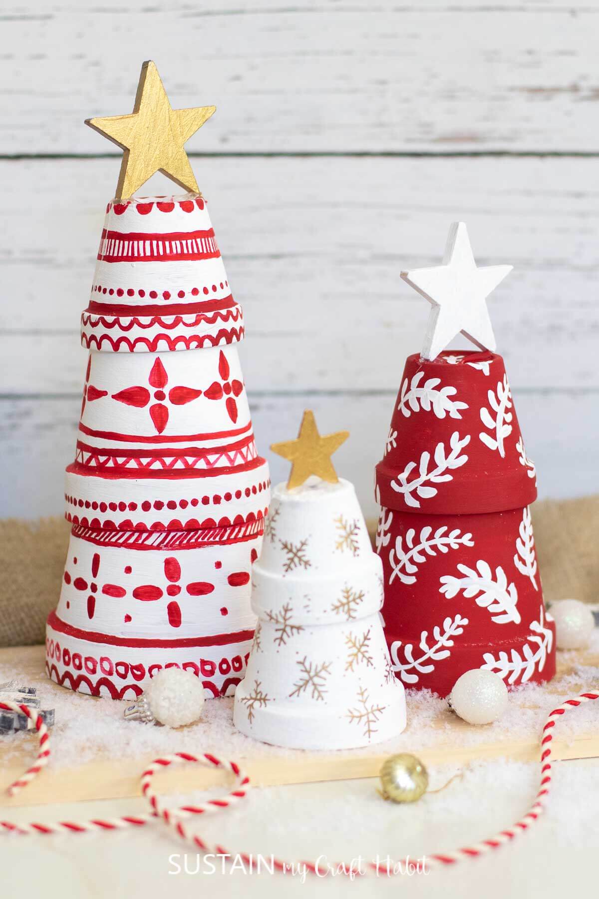 Budget-Friendly DIY holiday decorations are these stacked pots painted with red and white and topped with painted wooden stars.