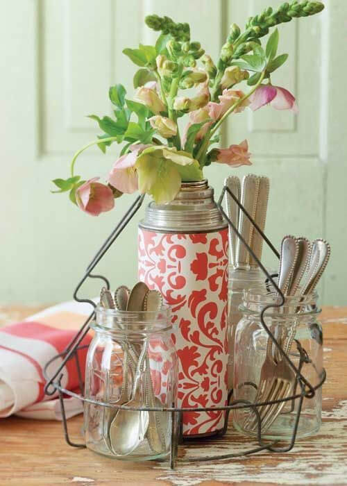 A vignette featuring clear jars of silverware and a red-and-white vintage thermos in the center.
