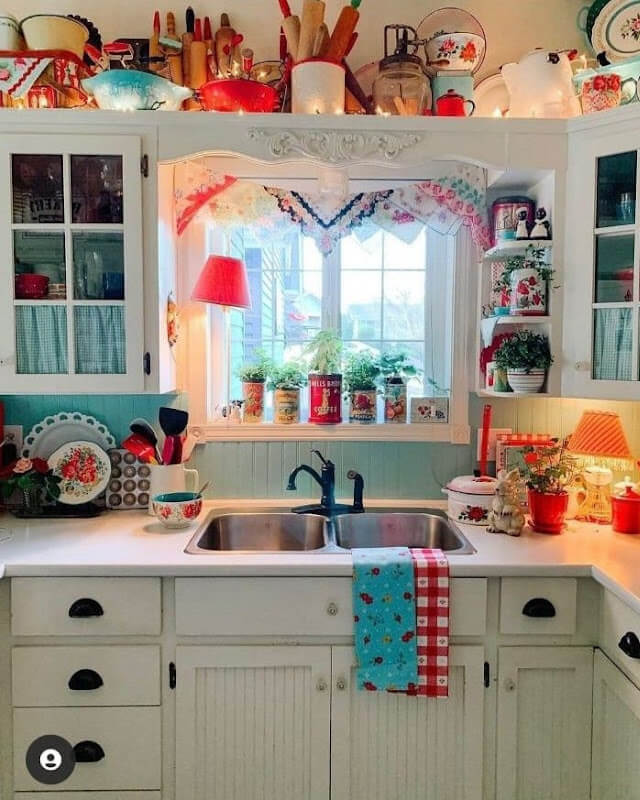 A white kitchen with glass-paned cabinets and lots of colorful decor.
