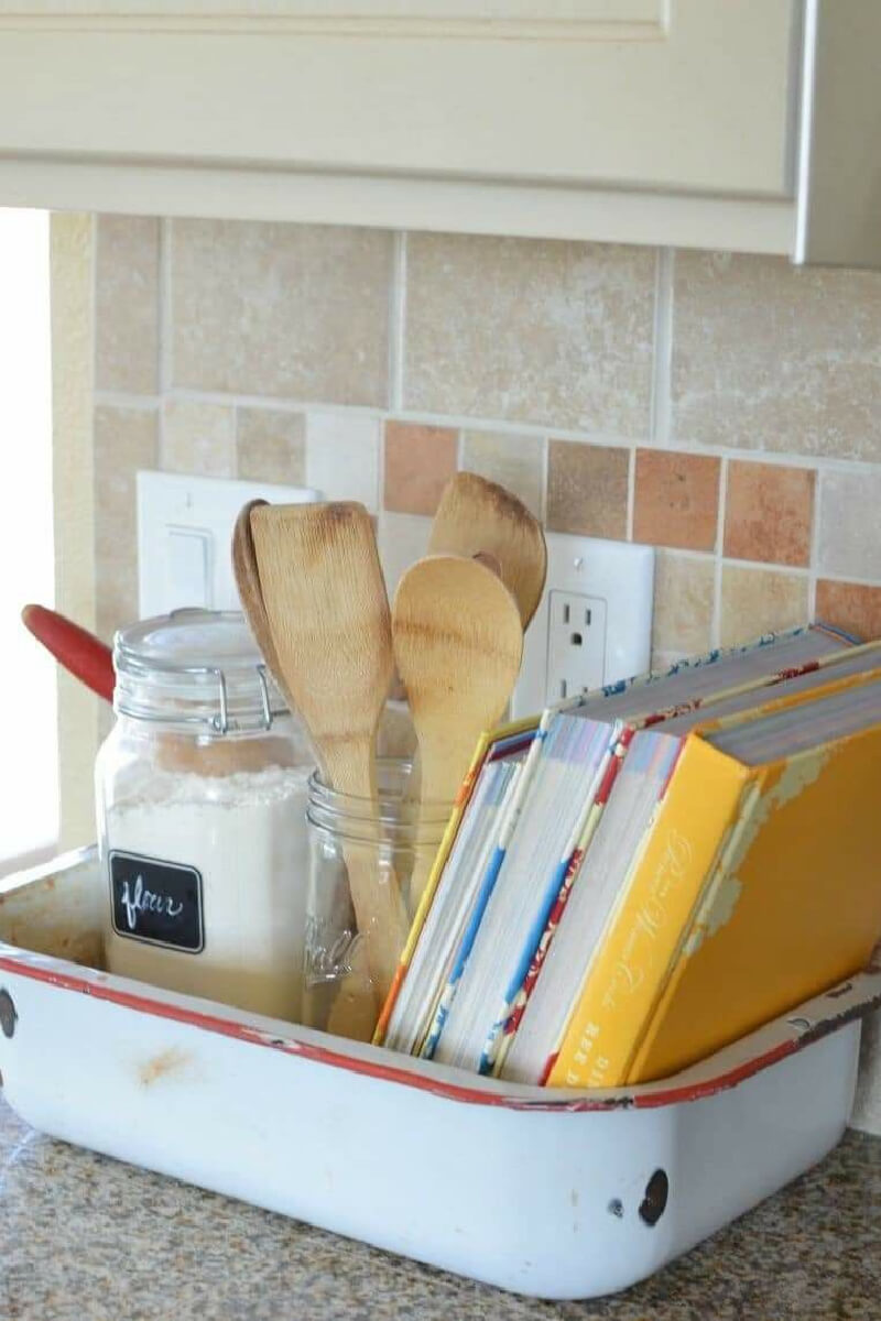A vintage enamel container with colorful cookbooks.