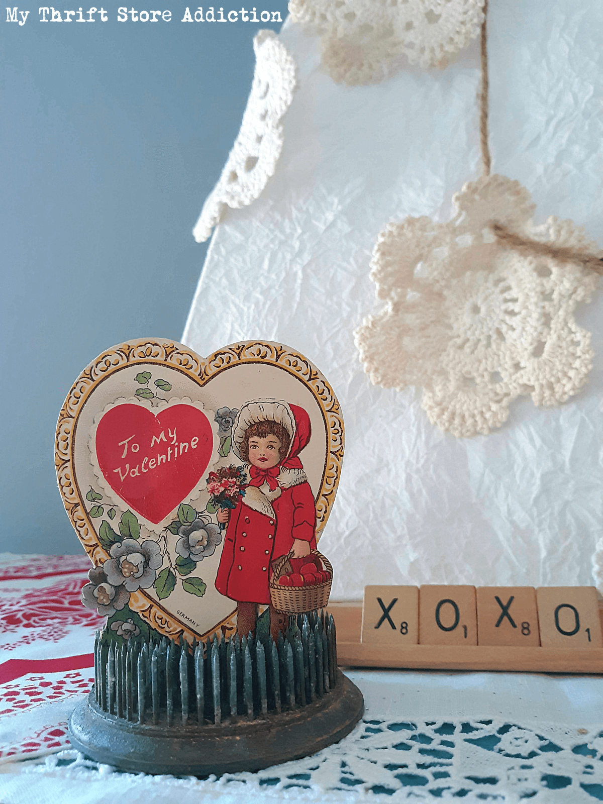 Vintage flower frog with Valentine's card, white crocheted doilies, and Scrabble letters.